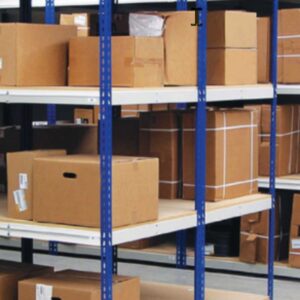 Shelves filled with various sizes of cardboard boxes, some with labels, rest on Borroughs Shelving systems featuring blue metal supports and white wooden boards. The setting appears to be a warehouse or storage facility.