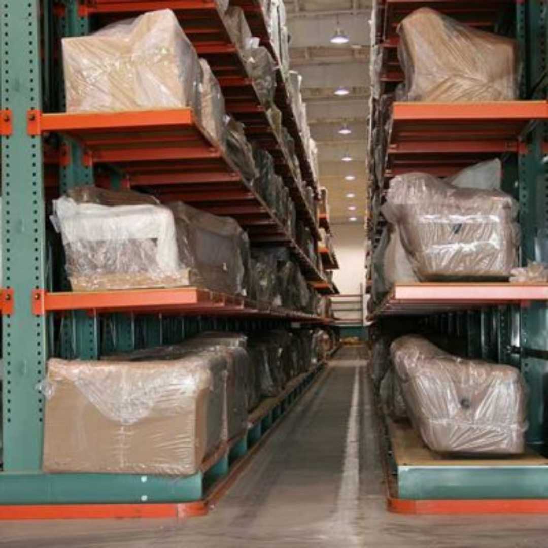 Long shelves of cantilever pallet racking holding large furniture pieces wrapped in protective plastic