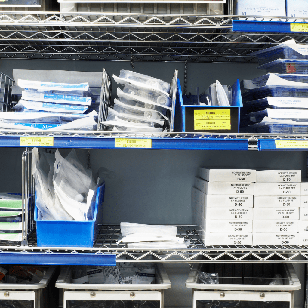 Shelves filled with organized dental supplies, including boxes, blue containers, and sealed instruments. With Pegasuss RFID Failsafe Medical Inventory System, items are stored neatly in a medical or dental office setting, with labels and tags visible on various packages.