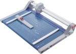The Dahle 550 Professional Rotary Trimmer has a 14 cut length, features a blue and gray design with a transparent guide, includes a measurement grid on its surface, and uses a sliding blade on a metal bar for precise cuts.