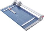 The Dahle 552 Professional Rotary Trimmer boasts a sleek blue and silver design, a sliding blade on a guiding rail, and a 20 cut length for precision. It features measurement grid lines and a red button for safety or convenience.