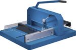 The Dahle 848 Professional Stack Cutter is an industrial paper cutter in blue, featuring a lever handle, metal guide, and clear safety shield. It precisely cuts up to 700 sheets at once and includes a measurement grid on the base for enhanced accuracy.