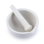 The MH-USA Mortar & Pestle, Porcelain, 160mm (500ml) set comes with a smooth white ceramic design, featuring a pestle resting inside the mortar that has a small spout for easy pouring and presents an unused appearance.