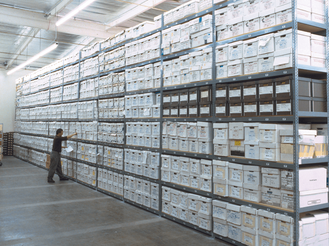 Wall of boltless shelving filled with labeled white records storage boxes