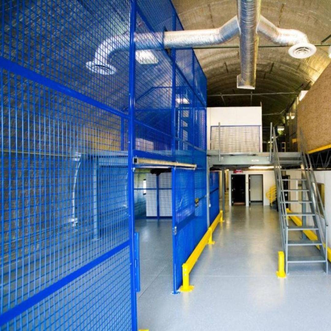 Blue wire mesh partition wall and mezzanine stair inside an industrial building