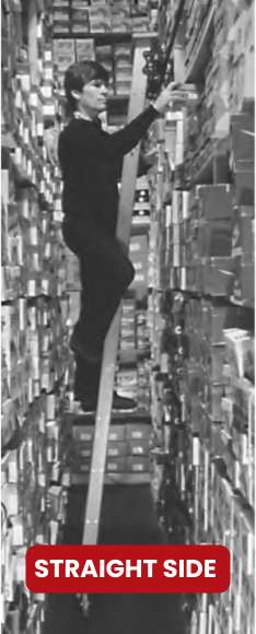 A person teeters on a narrow ledge between stacked boxes in a storage area, reaching for a box. A red sign at the bottom reads STRAIGHT SIDE, while nearby, sturdy options from Cotterman Ladders Company stand ready to offer safer heights.