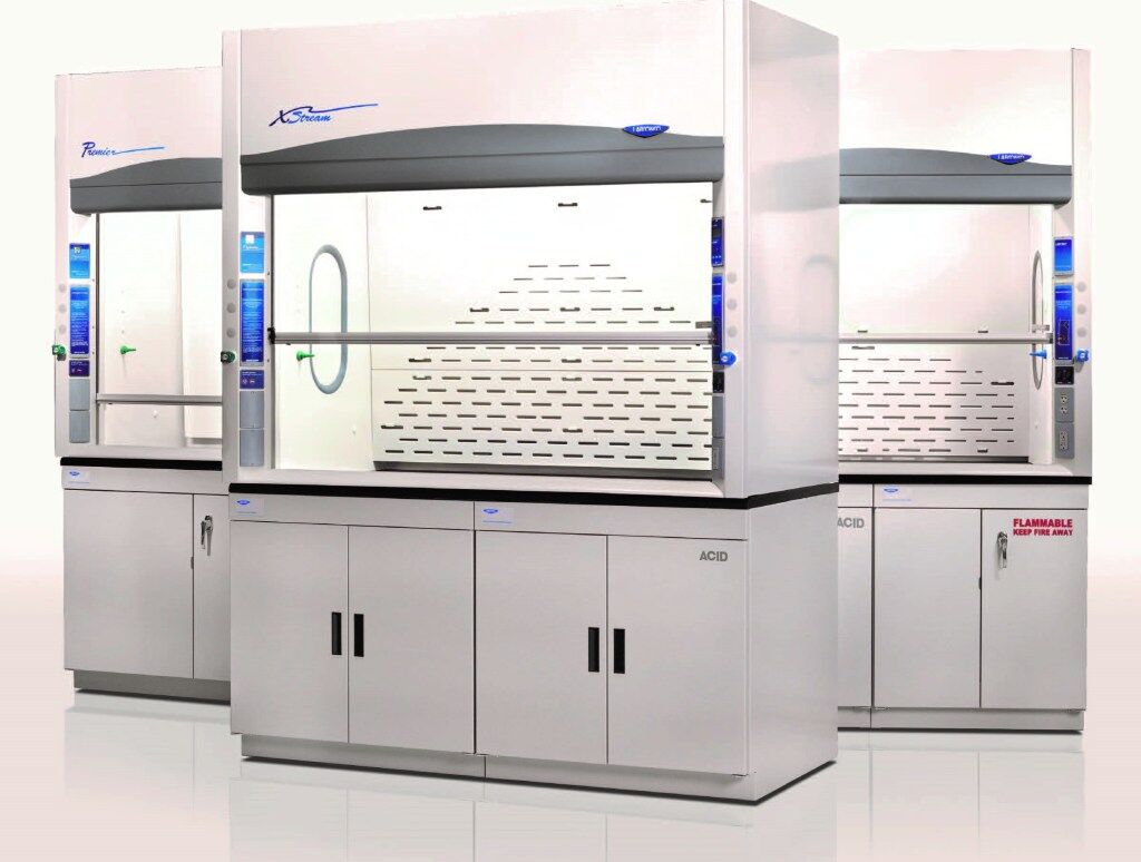 Three premium fume hoods with transparent glass panels and white cabinets stand in a bright, clean environment. Each features control panels with blue accents, ventilation grilles, and storage compartments labeled for acids and flammables, ensuring top-tier laboratory safety solutions.