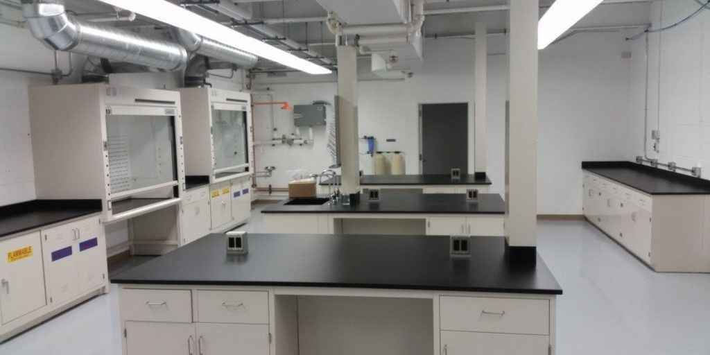 Fast-track lab casework and fume hood installation with black work surfaces and overhead ductwork