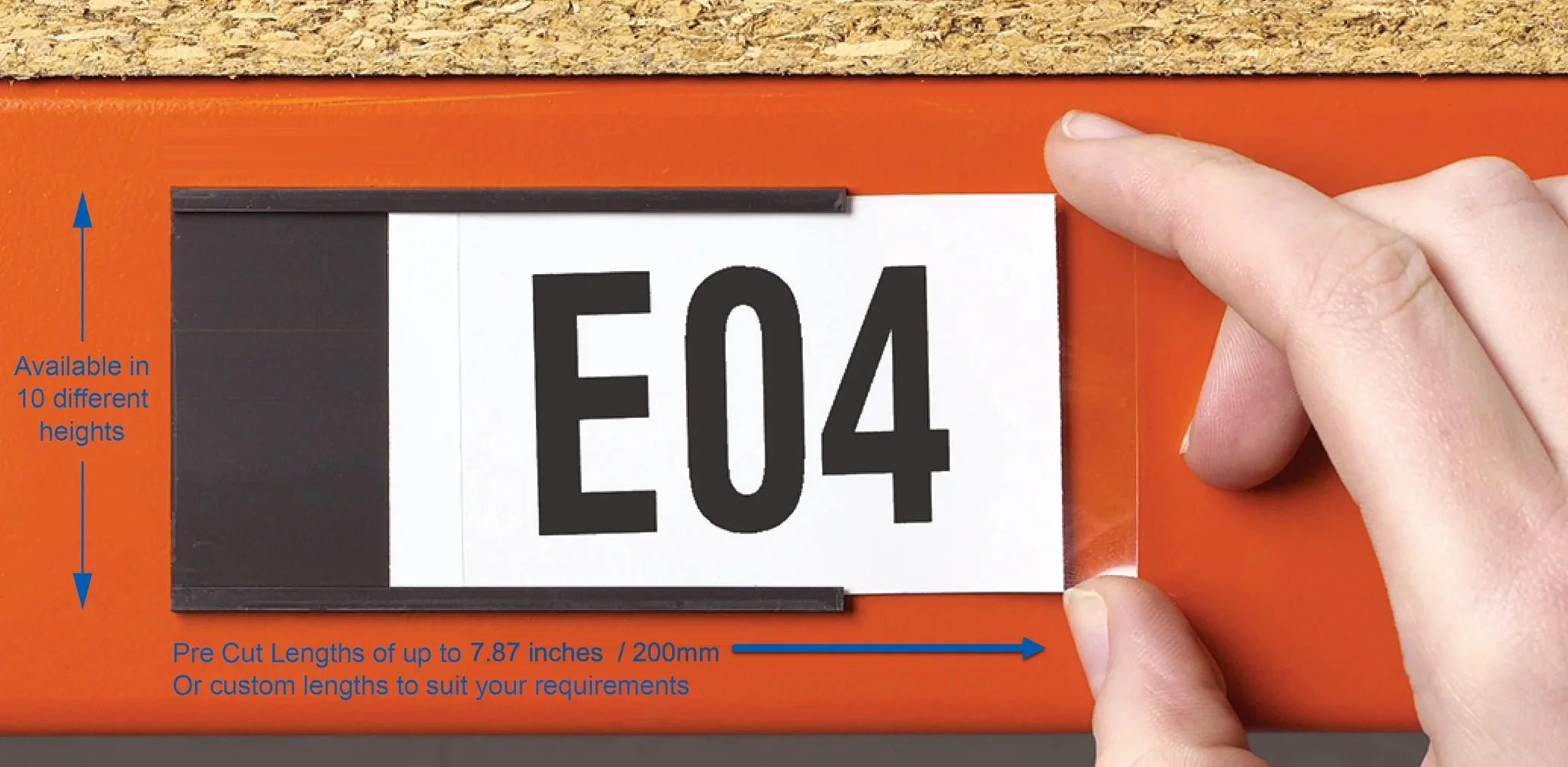 Hand applying a pre-cut white shelf location label reading E04 to an orange racking beam, illustrating custom pre-cut label lengths up to 200mm