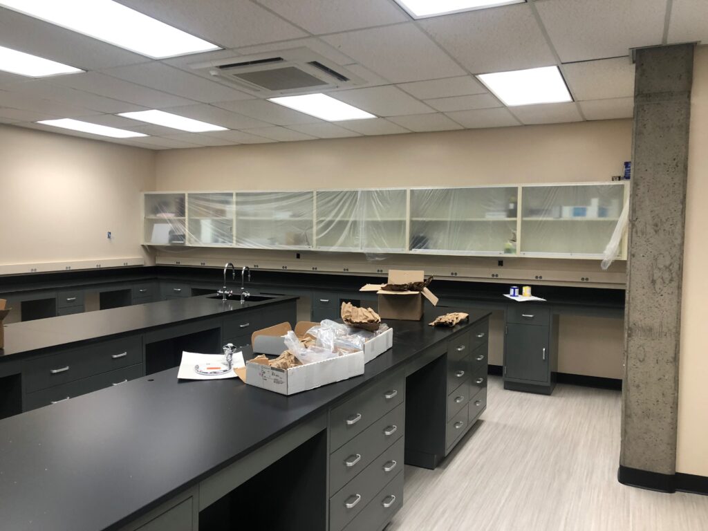 Long perimeter bench run at Weber State University with upper glass-front wall cabinets above and drawer cabinets below