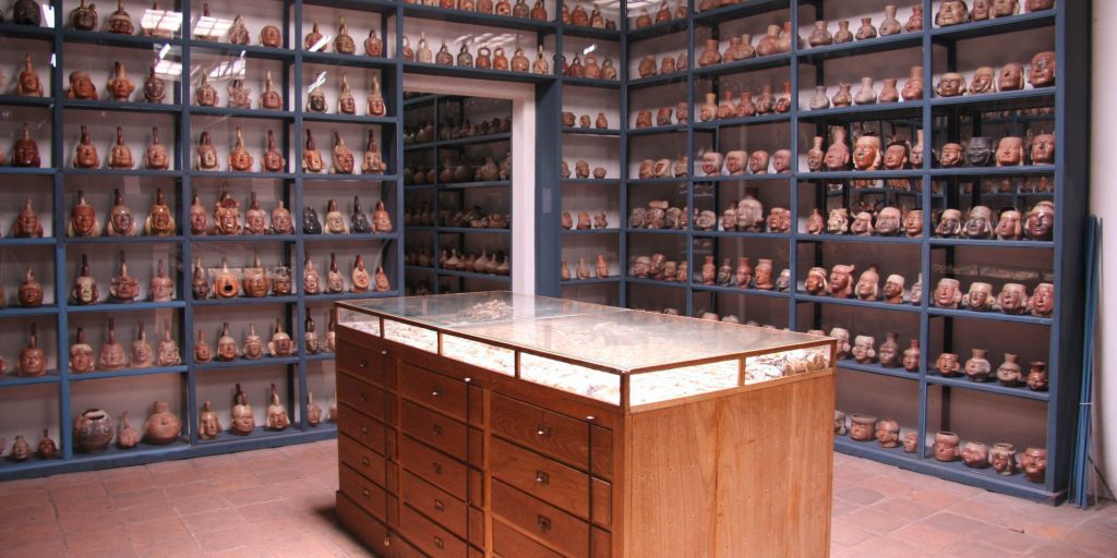 A promotional graphic for the "AIA Museum Storage Course" by Material Handling USA. The image features a sleek, modern storage system with high-density mobile shelving units, designed specifically for museum collections. The shelving is filled with various artifacts and artworks, showcasing efficient and organized storage solutions. The background includes the Material Handling USA logo and branding elements, emphasizing the company's expertise in museum storage solutions.