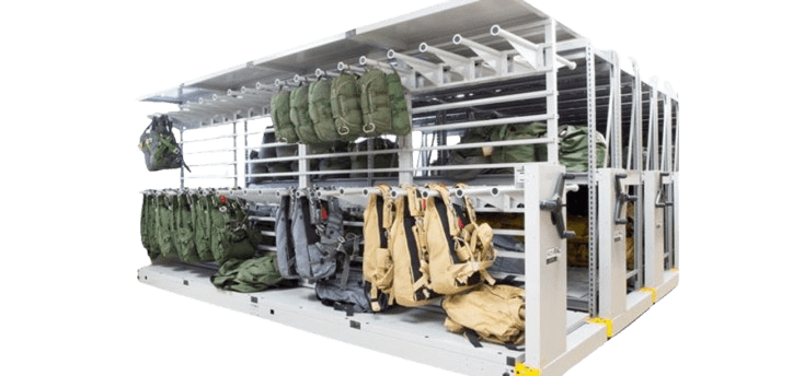 Secure mobile shelving serves as the backbone of this storage system, with multiple compartments holding green and tan backpacks and gear. Metal racks are organized in rows for efficient storage and retrieval, embodying the precision needed for military storage solutions.