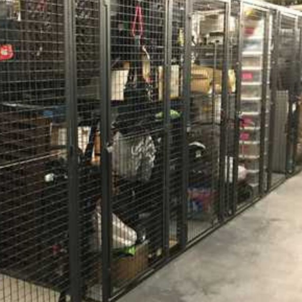 A row of metal storage lockers, essential in property management, is filled with assorted items like boxes, bags, and plastic containers. The mesh doors offer a glimpse inside, suggesting a well-organized area for equipment and supplies.