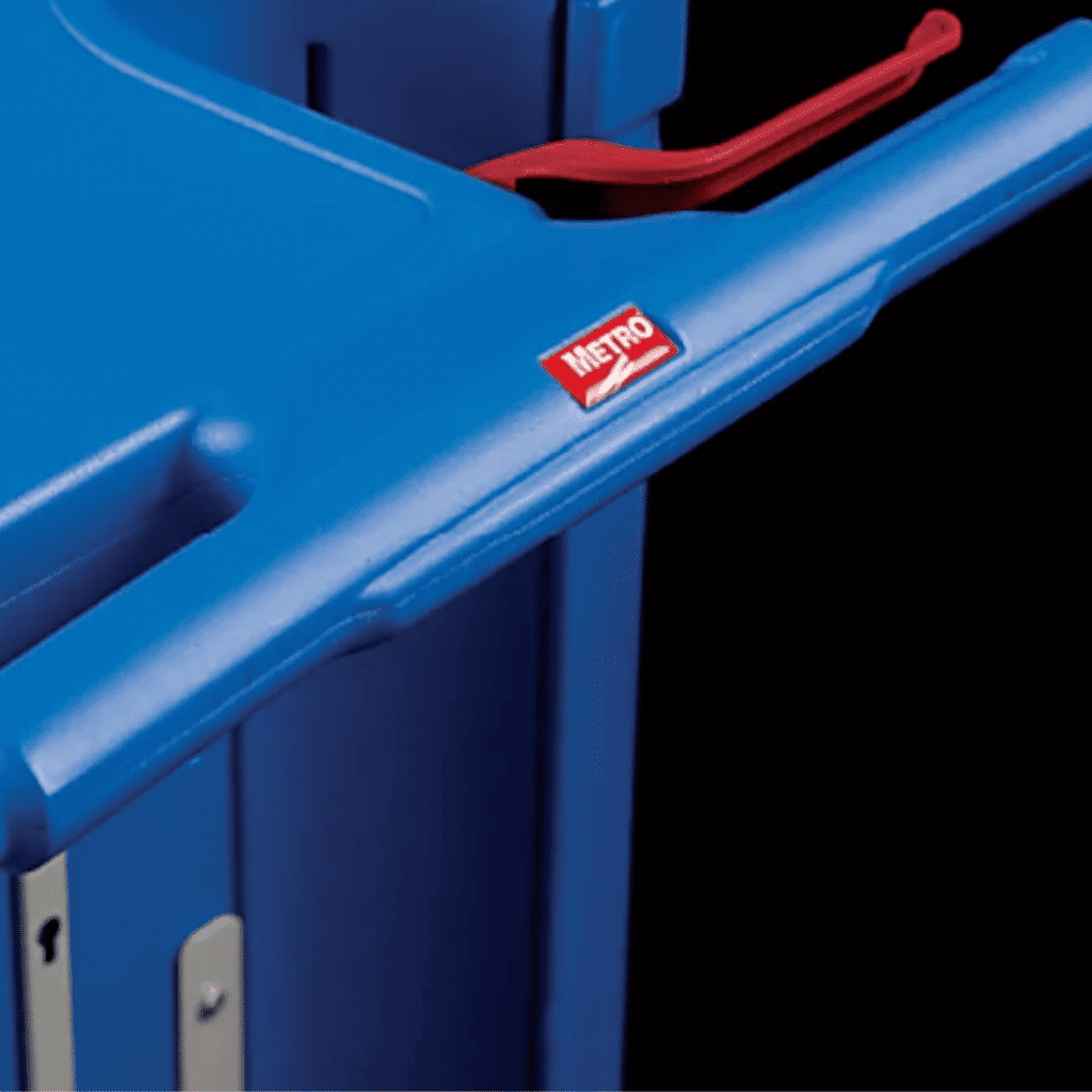 Close-up of a blue Lifeline Crash Cart featuring a red handle and a Metro logo sticker on the front. The carts smooth surface and defined edges are highlighted, with part of the compartment visible. The black background enhances its sleek design.