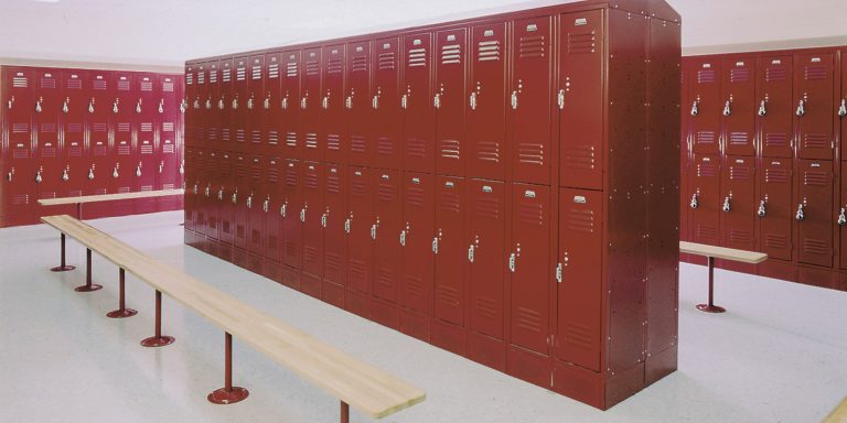 Red steel team lockers in two rows with wood benches in a school locker room