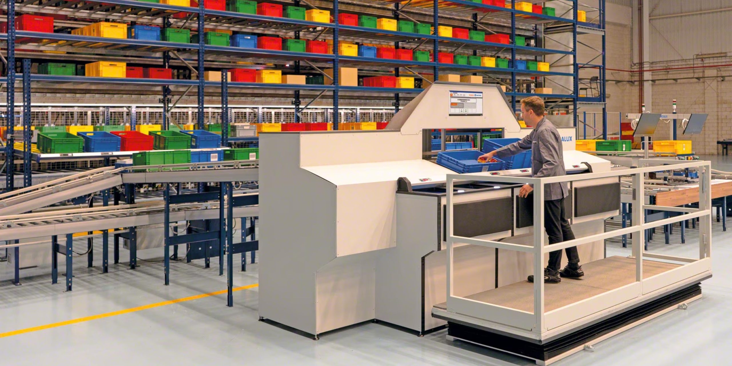 A person expertly operates a sorting machine in a spacious warehouse. Shelves with colorful bins and a conveyor belt highlight the efficient setting, perfect for implementing cutting-edge picking and packing solutions to manage inventory seamlessly.