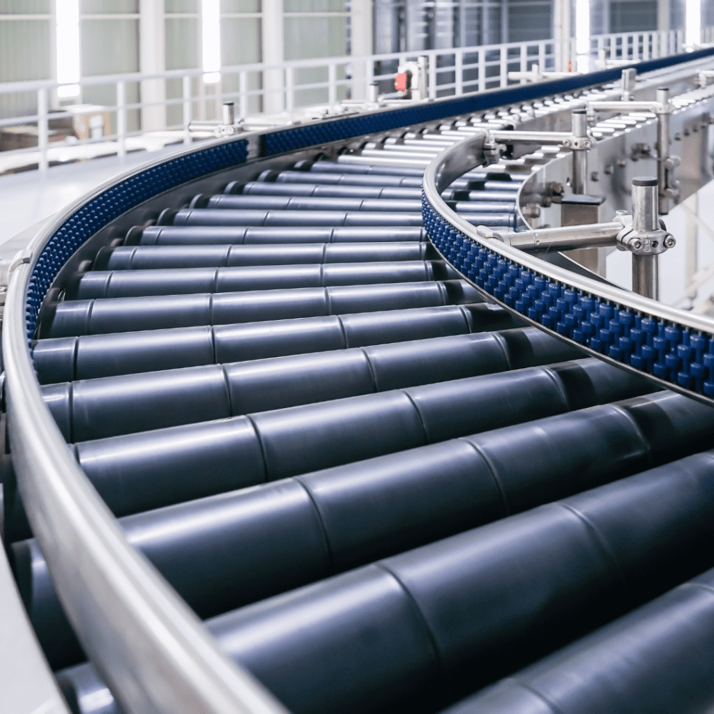 A close-up view of a modern industrial conveyor belt system, featuring black rollers and blue guiding rails, showcases the art of material handling in a brightly lit warehouse. The conveyor elegantly curves through the space, creating a dynamic and clean industrial gallery scene.