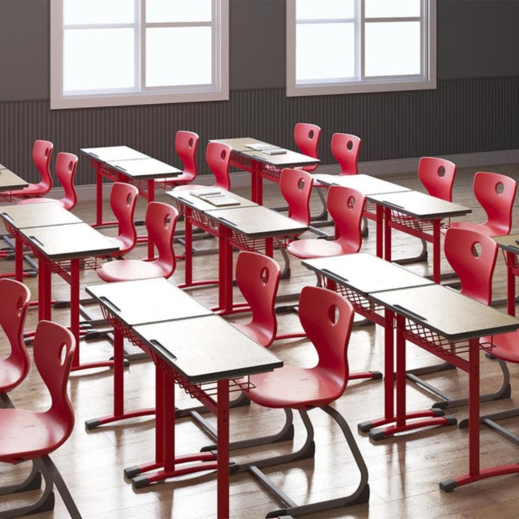 The Department of Education classroom features rows of empty red chairs and paired desks with metal baskets. They face a wall adorned with large windows, while the wooden flooring adds a touch of warmth to the learning environment.