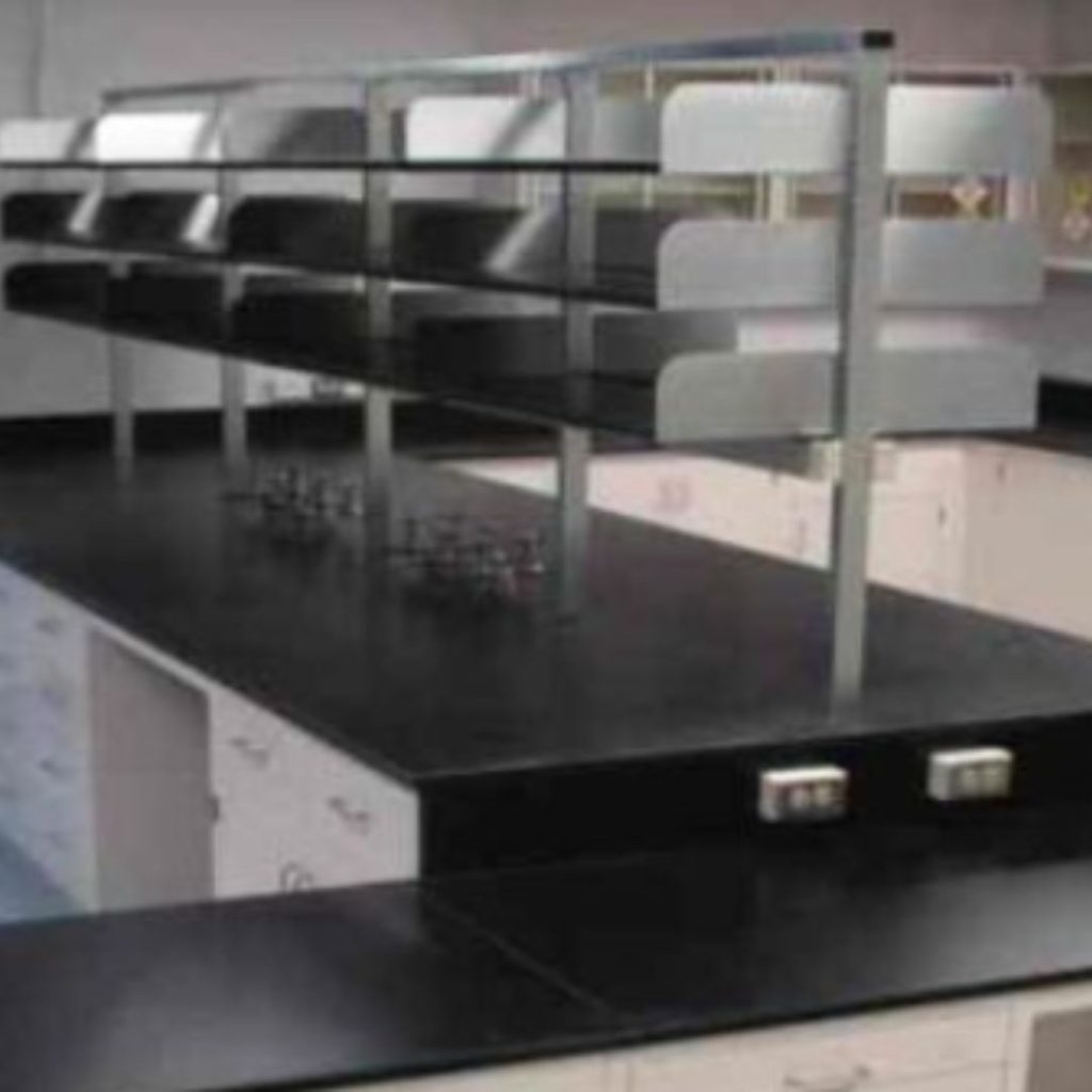 The empty laboratory, designed for the Department of Mining and Gas, features black countertops, white cabinets, and metal shelves. Electrical outlets punctuate the counters, paired with essential lab fixtures. Bright lighting enhances the sleek surfaces throughout the space.