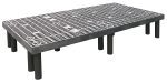 The Quantum Polymer Dunnage Rack, made in the USA from polyethylene, supports up to 1500 lbs. It features a vented plastic platform with a grid-like surface and circular patterns, supported by cylindrical black legs for enhanced durability and stability.