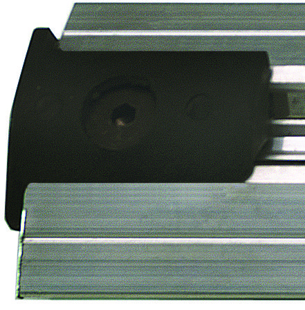 QESTP.jpg Close-up of a metallic linear rail system with a black carriage block featuring a grooved design. It includes the Quantum End Stop Kit with two end stoppers and a drill bit for precise alignment. The block partially covers the rail, showcasing a recessed center hole.