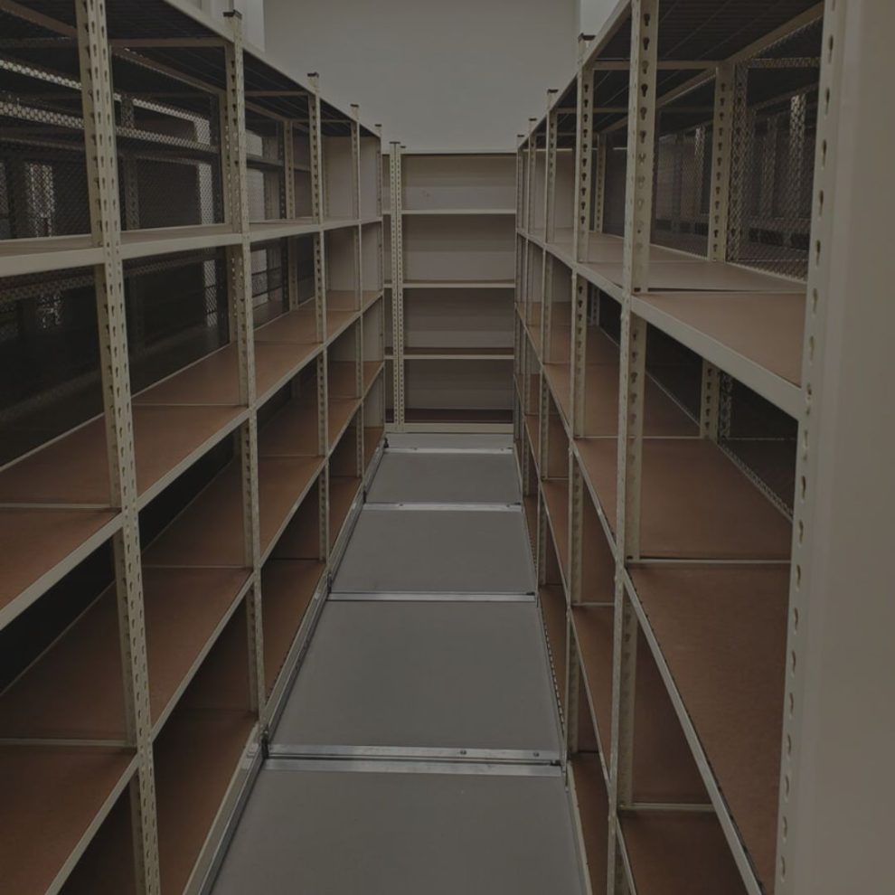 Organized stockroom aisle with steel shelving stocked with cartons and parts