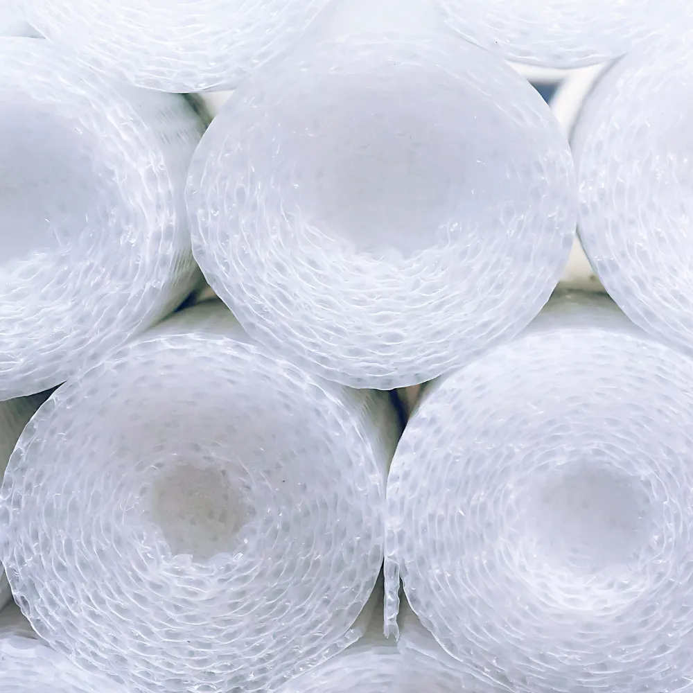 Close-up of multiple tightly rolled and stacked sheets of clear bubble wrap, creating a symmetrical, repeating pattern. The rolls are viewed from the side, highlighting their circular shape and translucent texture, a key feature in shipping supply wholesale.