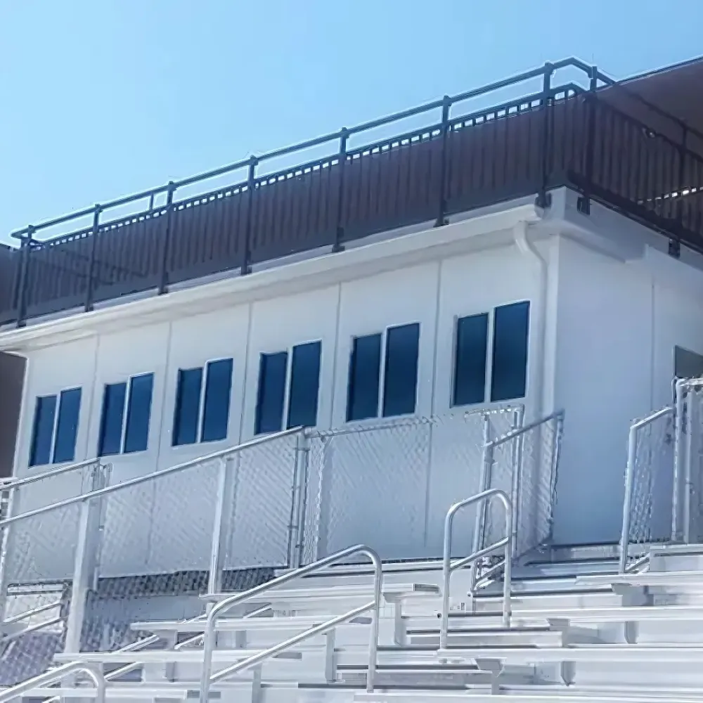 White prefabricated press box with a long window band above bleachers