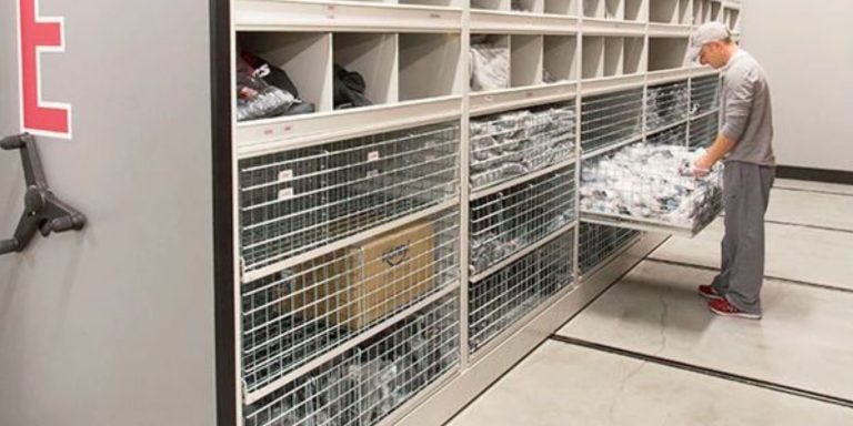 Staff member organizing a pull-out drawer of athletic equipment in a storage room
