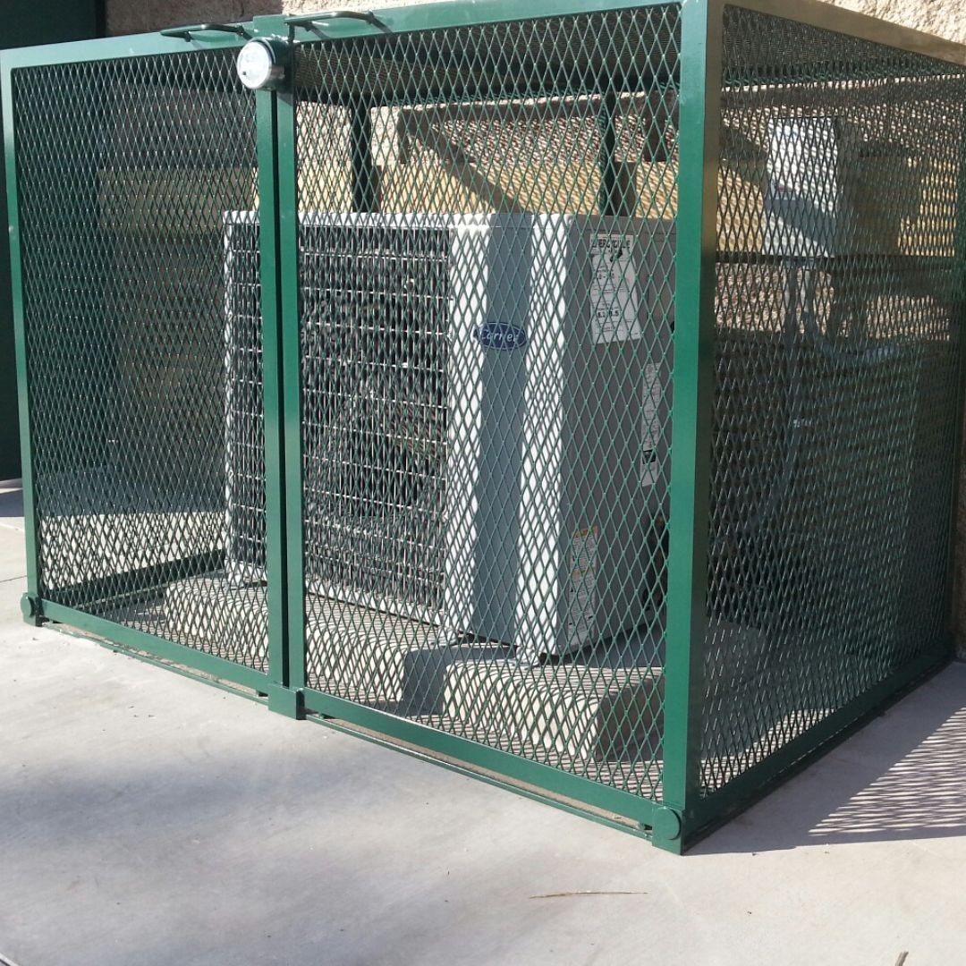 Green expanded metal security cage enclosing an outdoor condensing unit on a concrete pad