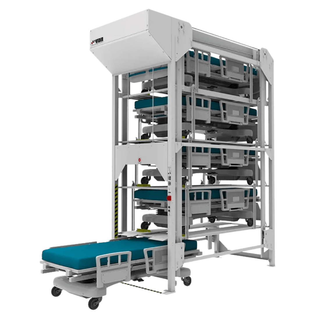 A vertical storage system featuring Automated Storage Solutions, holding multiple hospital beds stacked on metal racks, with one hospital bed partially extended from the bottom for easy access.