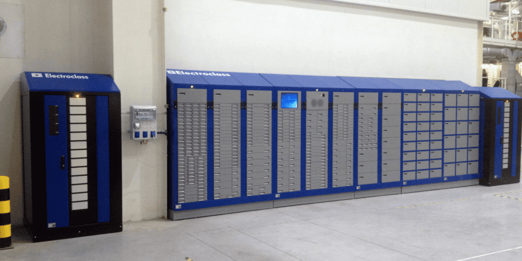 Blue and gray industrial storage lockers and cabinets, labeled “Electroclass,” are arranged along a wall in a clean, spacious indoor facility with a light-colored floor and walls.