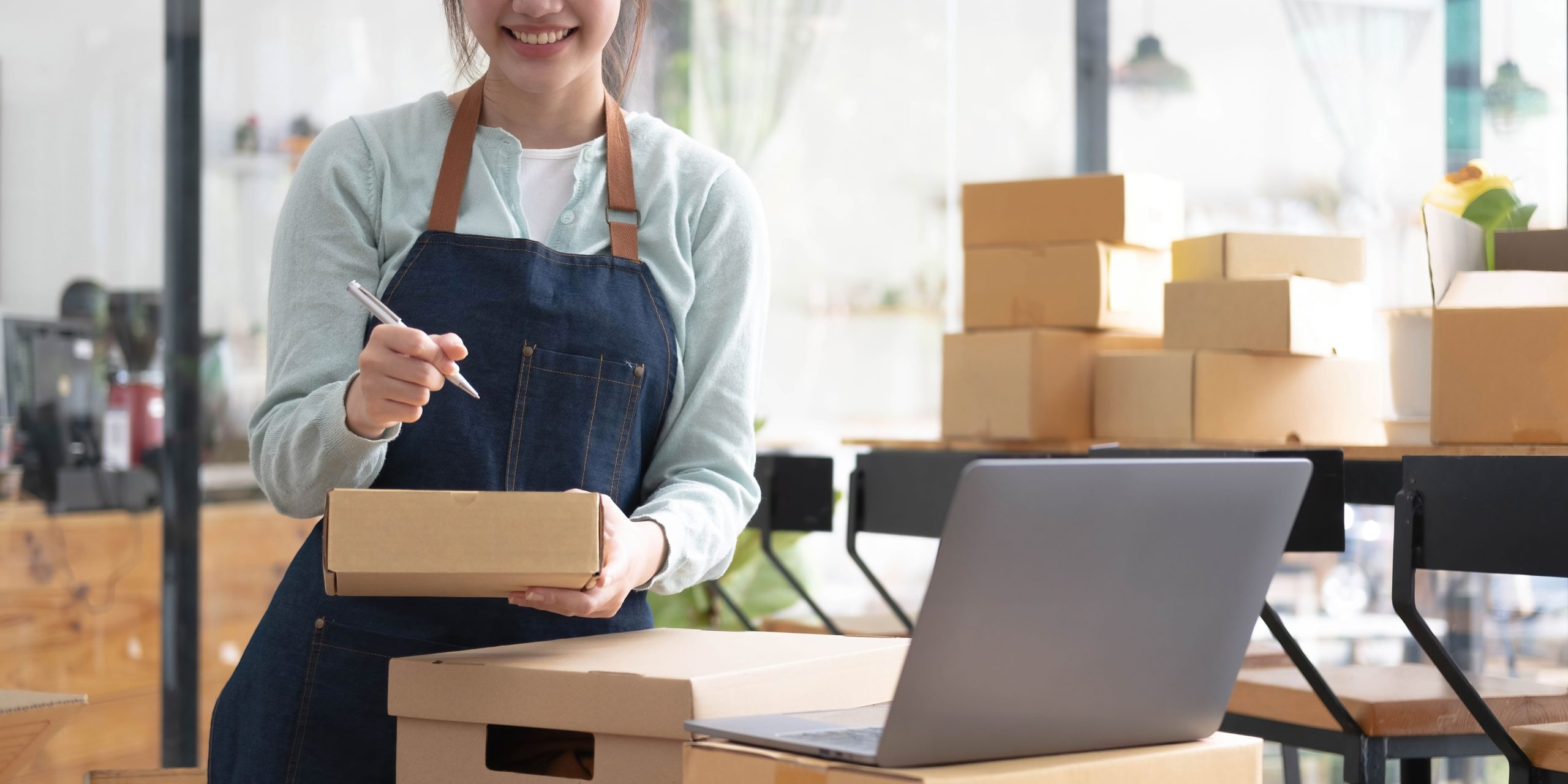 Business owner holding a corrugated box while comparing wholesale shipping supplies