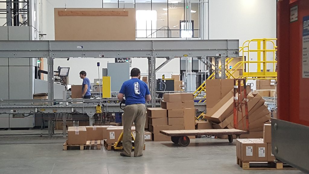 Warehouse workers using a conveyor and pallet rack area during distribution operations