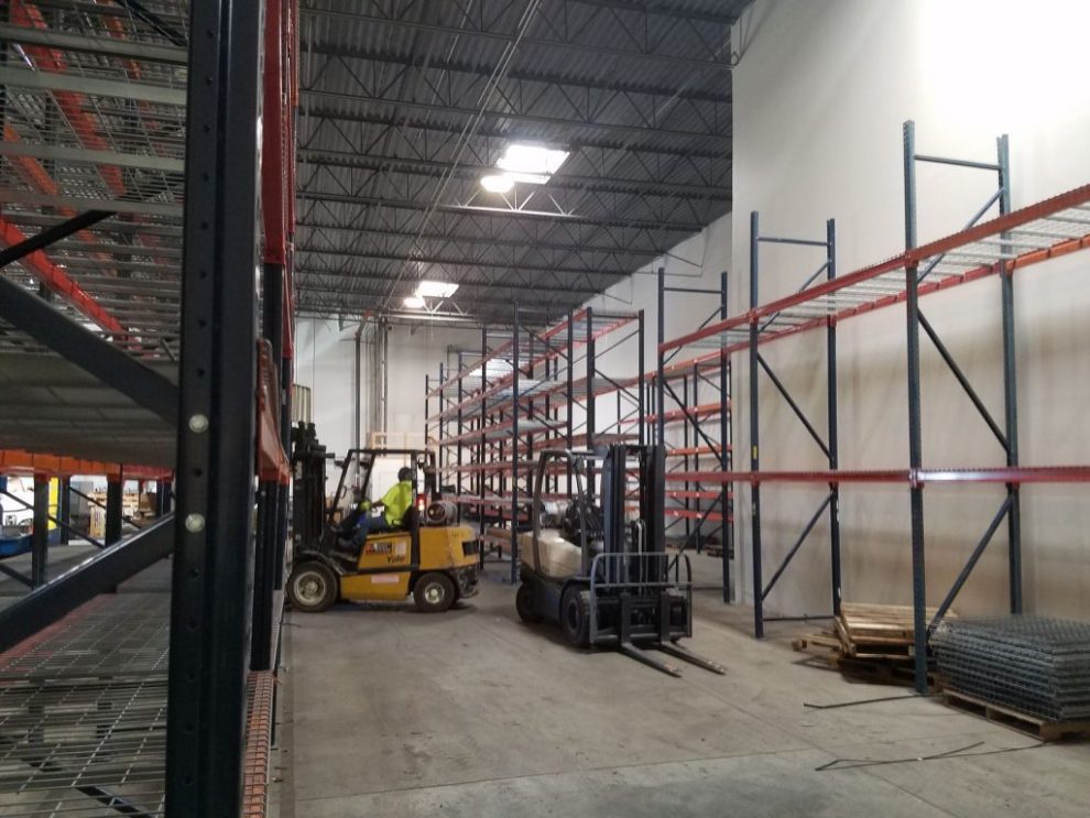 Forklifts working in a warehouse with tall pallet racking bays