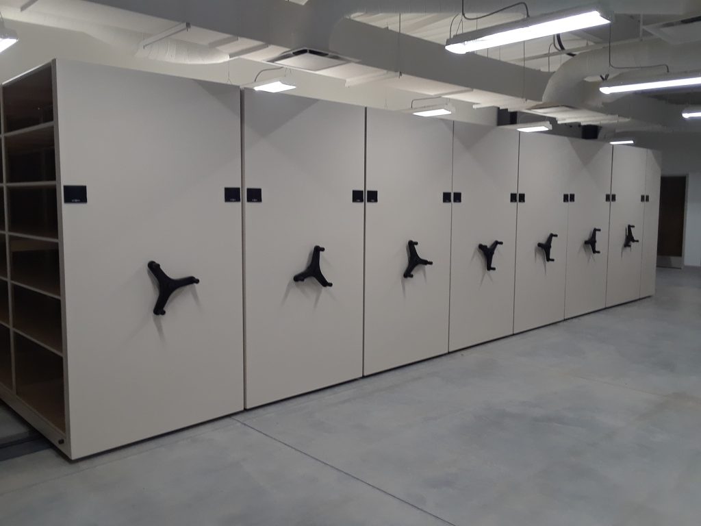 Interior aisle view between mobile shelving carriages showing cubby sections at South Jordan City Hall