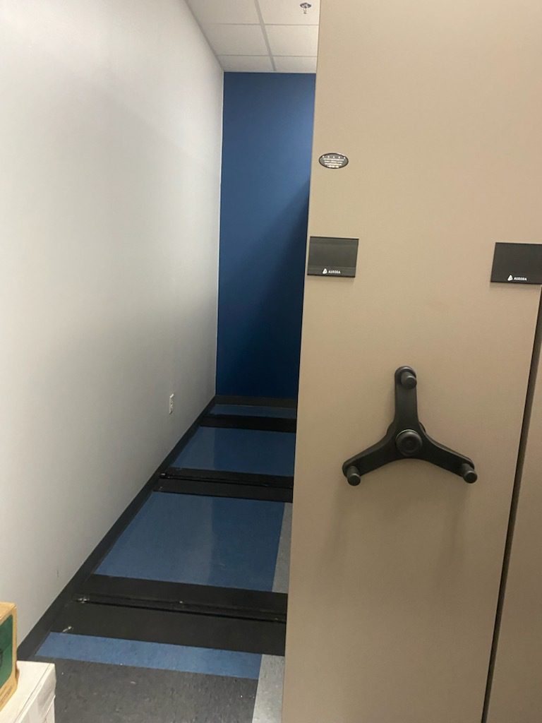 Tan Aurora mobile shelving end panels with three-spoke drive handles in an evidence room