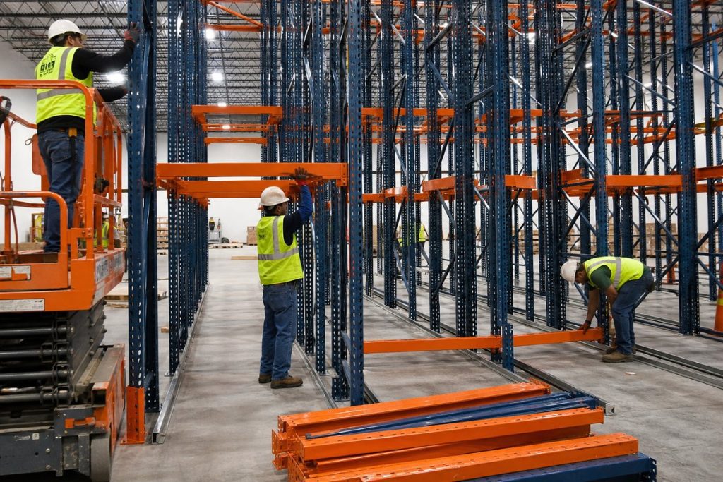 Workers installing drive-in pallet rack system