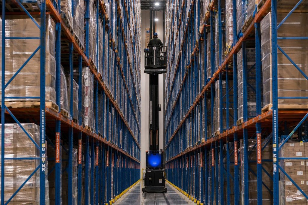 Very narrow aisle warehouse with turret trucks and tall pallet rack