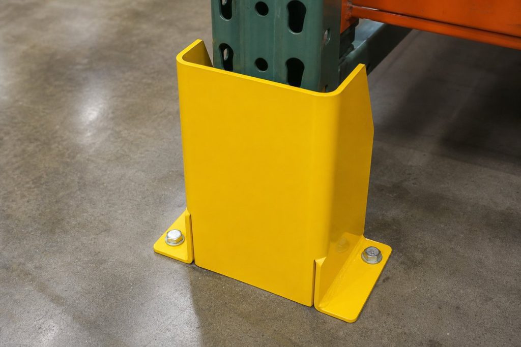 Yellow steel column protector bolted to the floor around a pallet rack upright