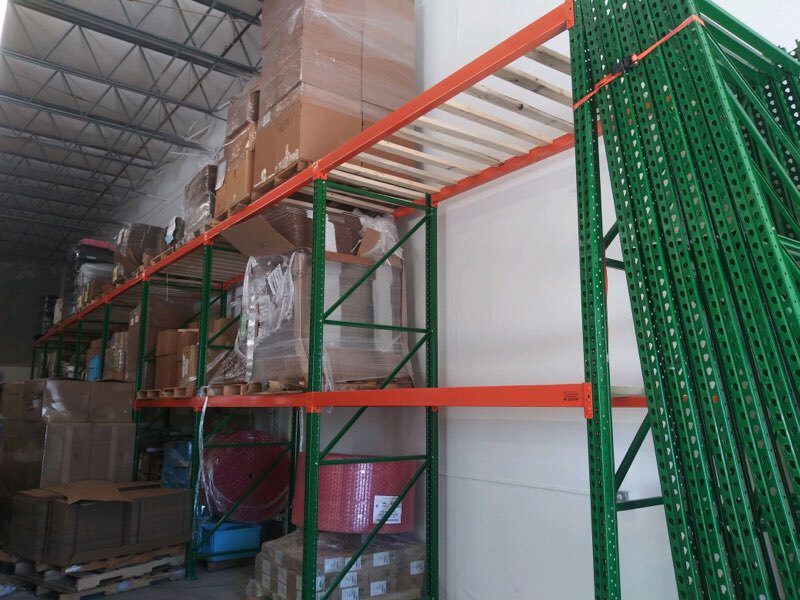 Multiple rows of pallet rack being installed with beam bundles on floor at Sanmina facility