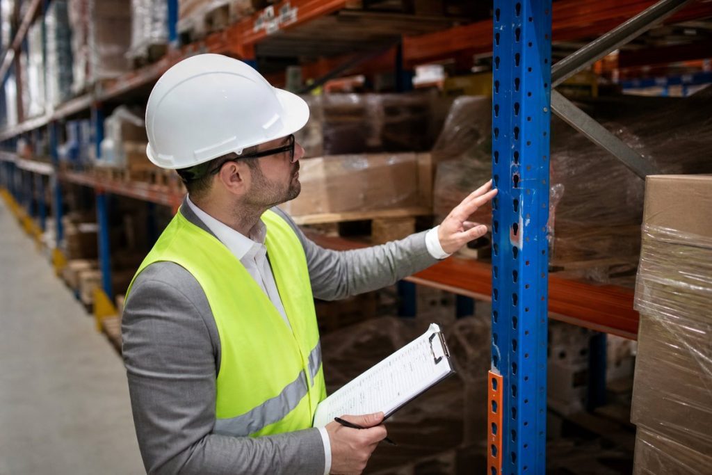 Safety inspector examining pallet rack for damage