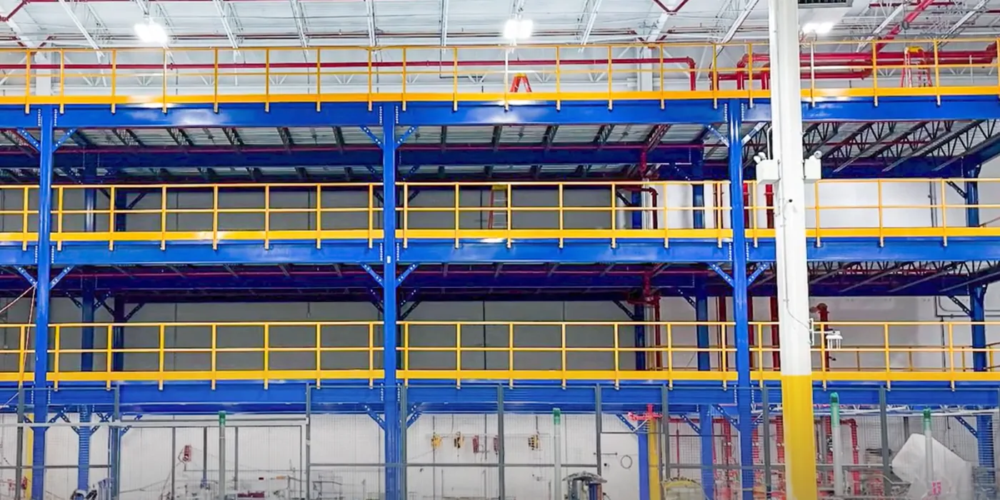 Multi-level steel mezzanine structure with stairs inside a warehouse