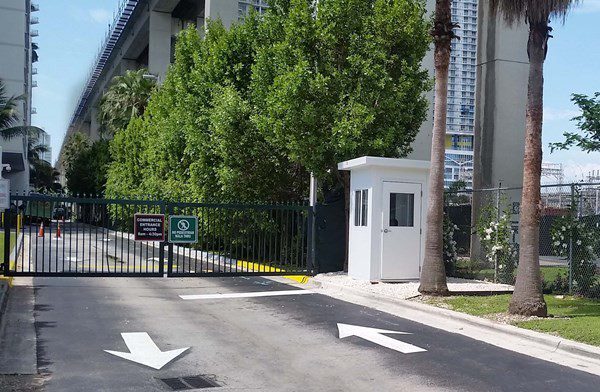 Guard booth beside a gated perimeter drive with barrier gate