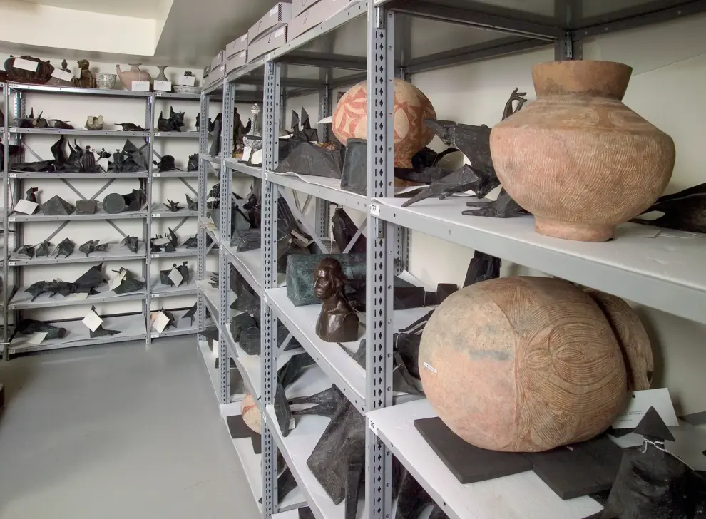 Steel shelving holding museum artifacts and archival objects on padded shelves