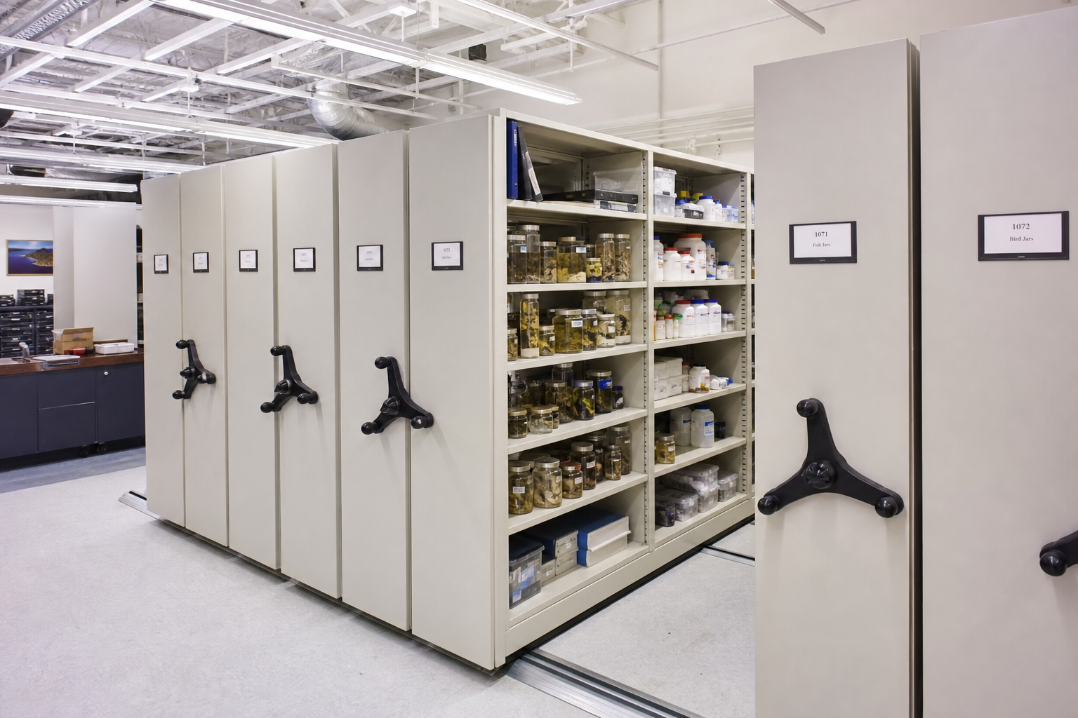 High-density mobile shelving with three-spoke drive handles in a research university laboratory