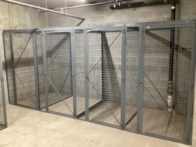Row of separate welded wire storage enclosures with individual locking doors