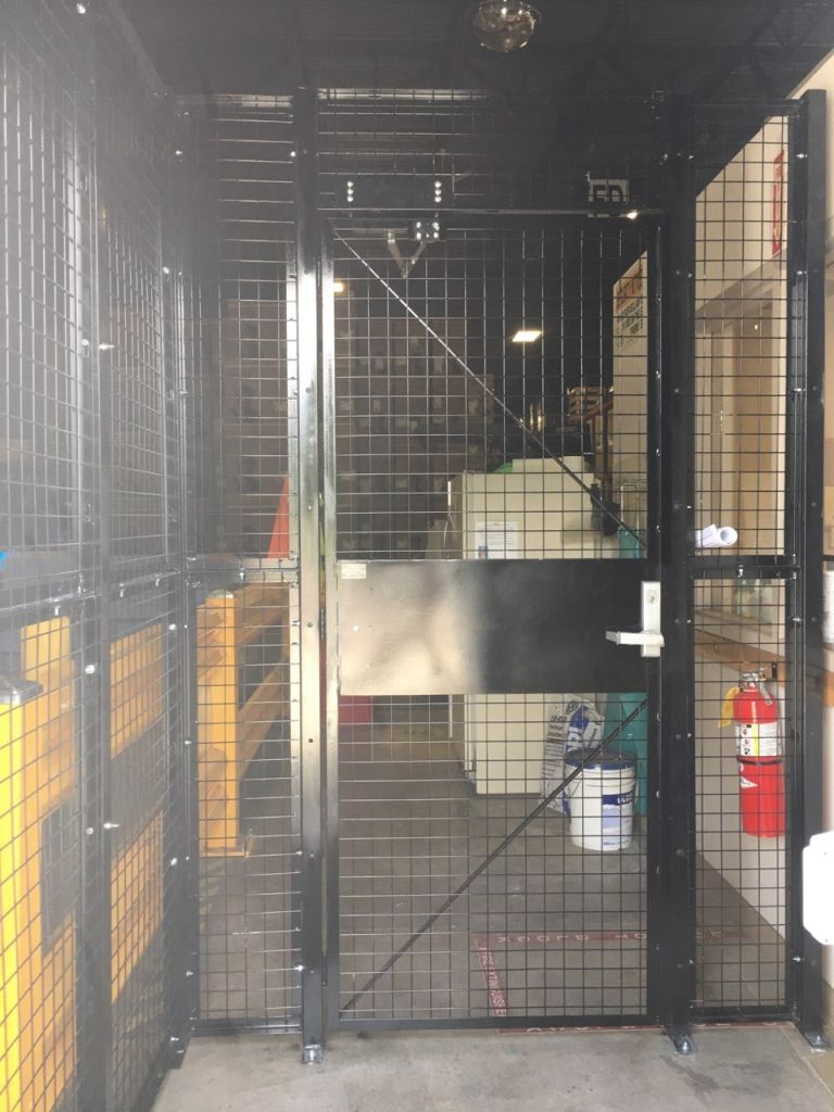 Installed black wire mesh cage door and partition inside a distribution warehouse