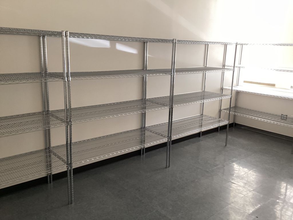 Chrome wire shelving units installed as a continuous run along a commercial stockroom wall