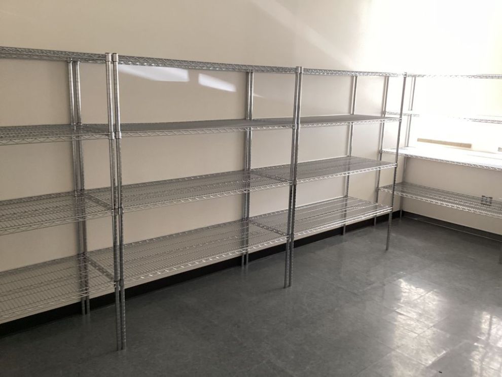 Chrome wire shelving units installed as a continuous run along a commercial stockroom wall
